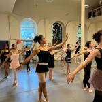 Adult ballet students practicing port de bras in the center