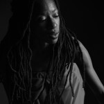A black and white image of a Black woman with long locs. 