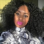 A Black woman with natural hair, pink lipstick and black and white turtleneck.