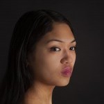 Keerati, a young Thai-American woman with long black hair and rose colored lips stares outward. Photo by Carrie Schneider. 