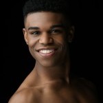 Smiling Black man with bare shoulders in front of a black background