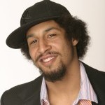 Smiling man wearing a black baseball cap, collared shirt and sportscoat