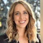 Photo of Jenny, a white woman with brownish blonde hair curled wearing a black blazer.