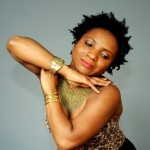 Woman stretched in pose with hands resting under chin, wearing two gold bangle bracelets