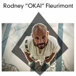 Smiling man wearing white gazing up into the camera, standing on a white and blue striped floor