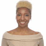 Smiling Black woman with blonde high top fade wearing small gold hoop earrings, copper lipstick, and a tan knit shirt