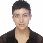 Nadia looks toward the camera with a relaxed expression, their head tilted to one side. They have short dark hair and light skin