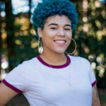 Background: trees and leaves Hair color: blue  Wardrobe: hoop earrings, a necklace, and a white t shirt with burgundy trimming.