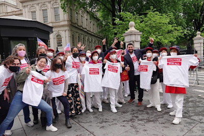 several participants at city hall posing with white and red tshirts that say 
