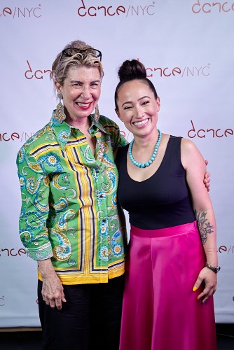 Two women, Carla Hoke-Miller and Alejandra Duque Cifuentes joyously take a picture together during the Dance/NYC DWR Initiative Launch Event. Behind them is a step-and-repeat with the Dance/NYC logo.