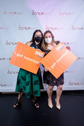 Two women joyously take a picture together during the Dance/NYC DWR Initiative Launch Event holding a poster that reads ‘I Got Counted’. Behind them is a step-and-repeat with the Dance/NYC logo.