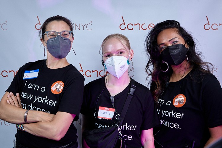 A volunteer joyously takes a picture with two Dance/NYC staff members at the Dance/NYC DWR Initiative Launch Event. Behind them is a step-and-repeat with the Dance/NYC logo.