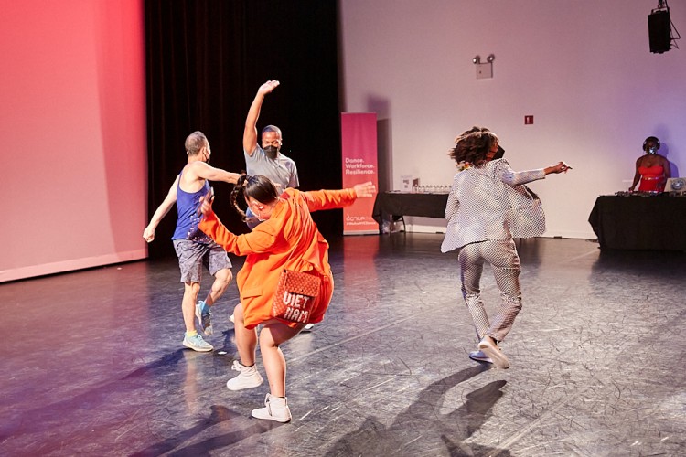 Four attendees are captured joyously dancing with each other during the Dance/NYC DWR Initiative Launch Event. They are seen forming a circle of rhythm in the process.