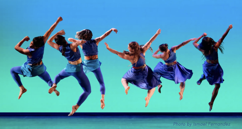An ensemble of 6 dancers airbound in a spiraling jump in unison onstage.