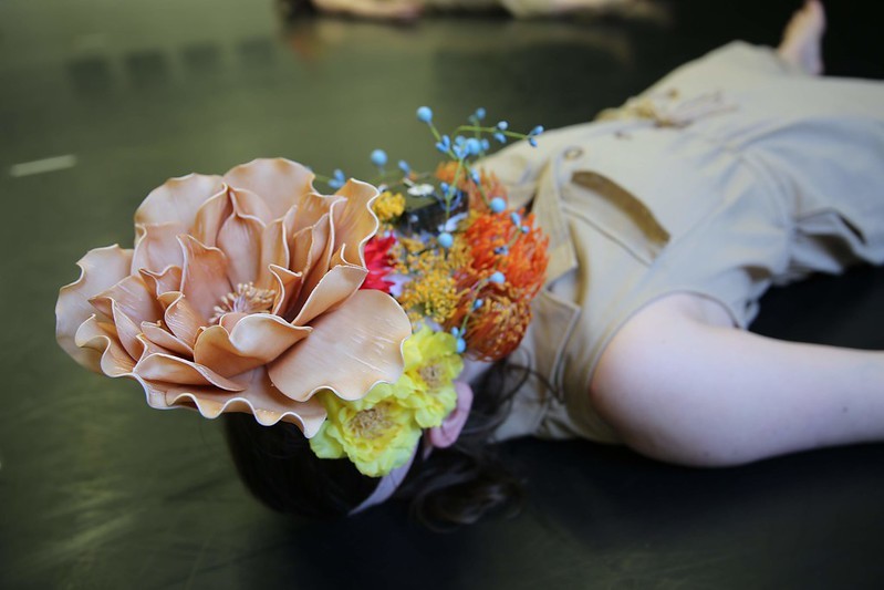 A closeup of a dancer with a floral m ask covering her face.