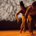 two dancers of color hovered over one another