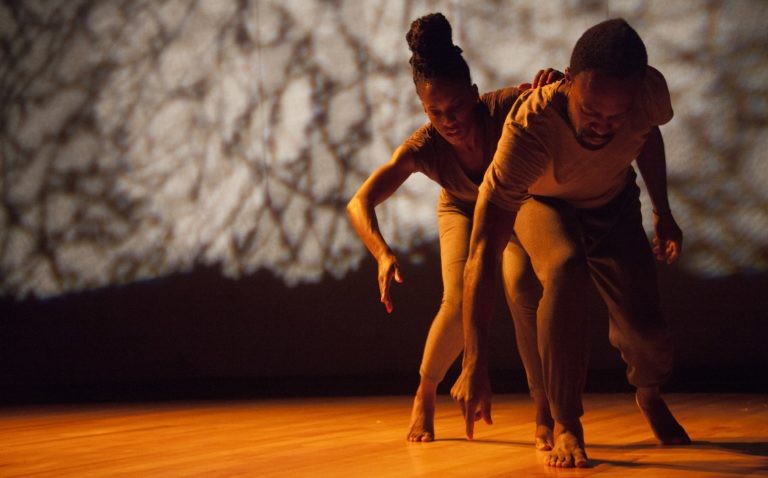 two dancers of color hovered over one another