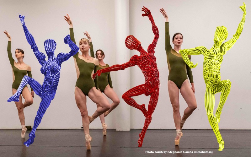 Dancers are posed with steel statues in bright vibrant primary colors. 