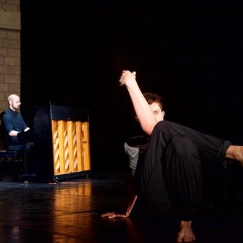 Image of a dancer sitting with legs crossed an one hand bent at the elbow 