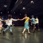 Several people holding hands and dancing in a circle.