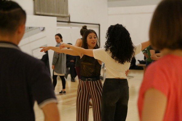 Alessandra stands arms spread demonstrating technique to a student.
