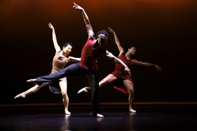 Three dancers in triangular formation each leaning towards standing leg with stage right leg extended 45 degrees side.