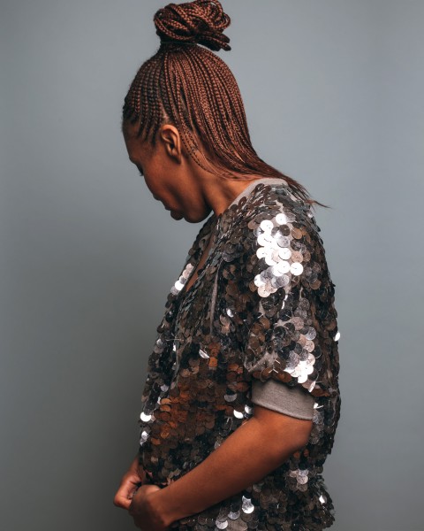 professional photo with black woman facing backwards with silver, sparkly short sleeve jacket!