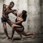 Two dancers in black outfits photographed in a concrete area
