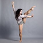 Dancer standing on one leg with arms outstretched and the other leg lifted into the air.