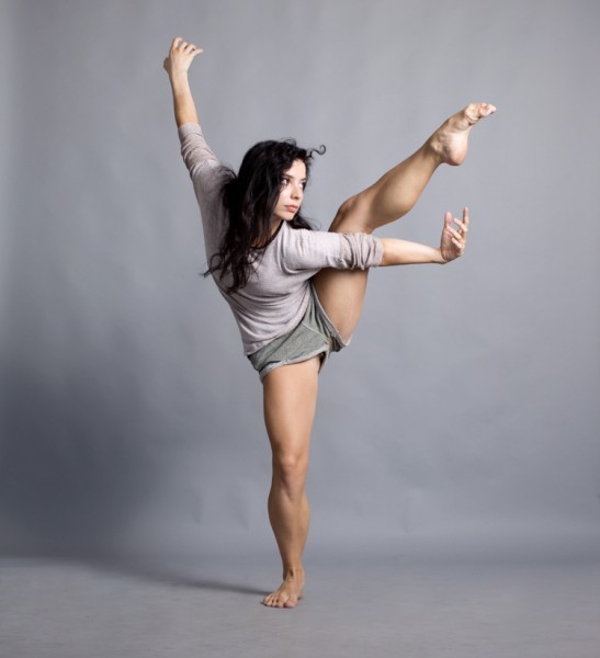 Dancer standing on one leg with arms outstretched and the other leg lifted into the air.