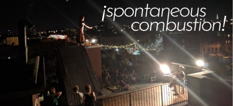 On a rooftop, a beam of lights connects a dancer reaching down towards a cellist. The audience looks on, seated on blankets