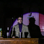 a bespectacled man behind a bar