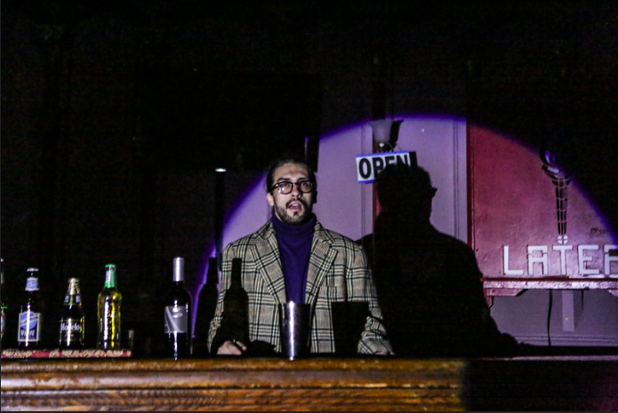 a bespectacled man behind a bar