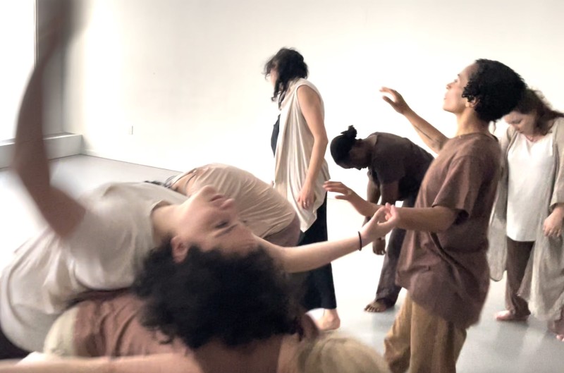 dancers in a studio beige clothing standing and in contact with others
