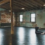 Dancer stretching in The Iron Factory dance studio - marley flooring, exposed brick walls, wooden beams