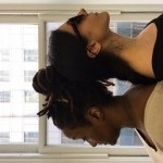 Two visually imapaired female dancers stand back to back in front of a window.