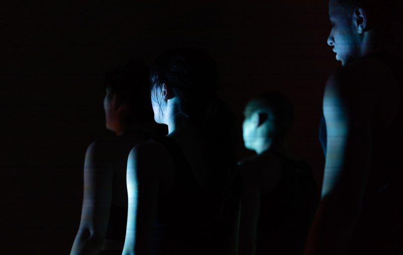 There are four people, moving through a blue-shadow-y light