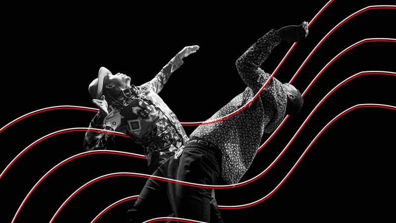 Black and white image of two male dancers facing toward one another.