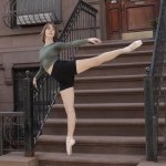 Full-body action shot of a female dancer in an arabesque in front of a NYC brownstone showcasing urban style