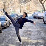 Full-body action shot of a male dancer in a dynamic pose on a New York City street, showcasing urban style
