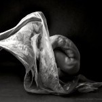 A black and white image of Peter in a crouched position with fabric floating above.