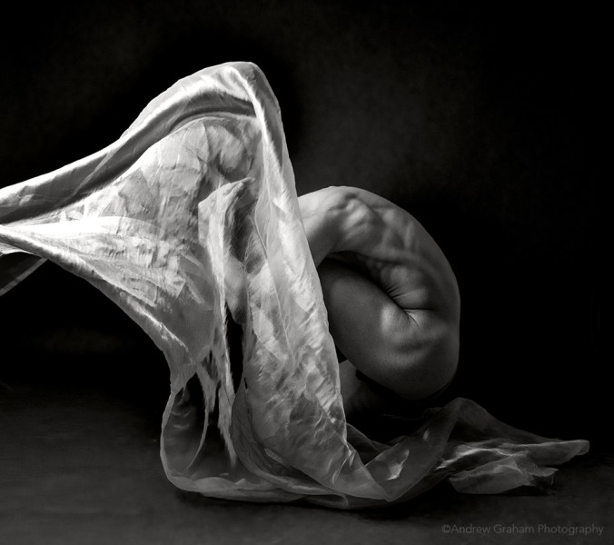 A black and white image of Peter in a crouched position with fabric floating above.