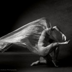 A black and white image of Peter in a crouched position with fabric floating above.