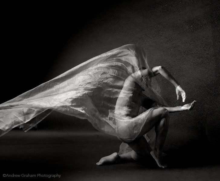 A black and white image of Peter in a crouched position with fabric floating above.