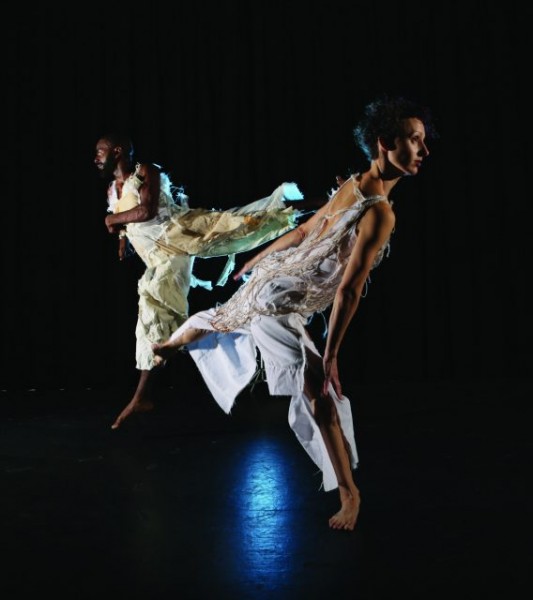 color photo of a black man and white woman in alternating arabesques wearing tattered constructed graments