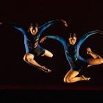 2 dancers jumping with bent legs and rounded arms