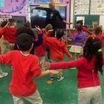 View of a Hip-Hop teaching artist in class with a group of 15 elementary school children