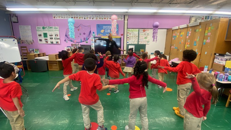 View of a Hip-Hop teaching artist in class with a group of 15 elementary school children