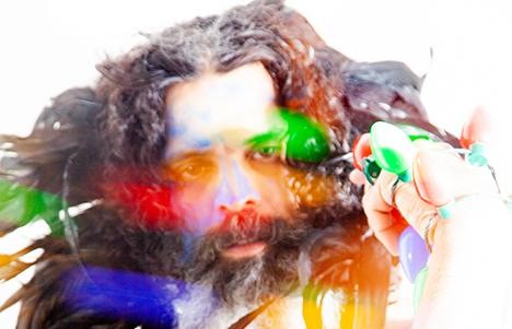 Artist headshot overlaid with multicolored lights