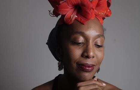 artist looks down with red hibiscus flowers on her head